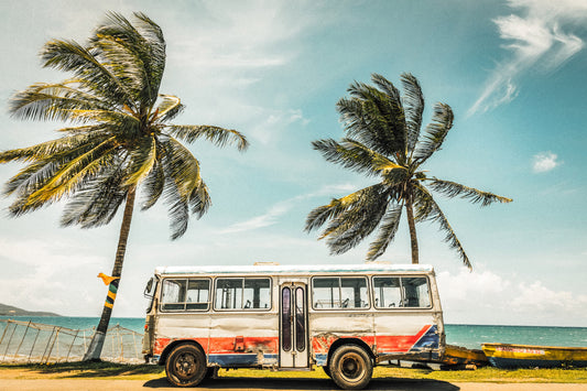 An idyllic beach scene with crystal clear turquoise waters, lush palm trees swaying in the breeze, and a vintage bus parked on the sand.