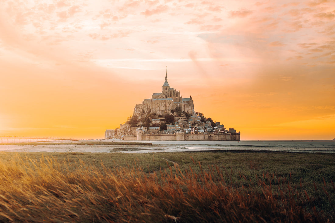 A stunning view of Le Mont St Michel in sunset, with its towering spires and medieval architecture.